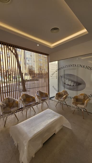 Reforma de Sala de espera de una clínica dental en Madrid con sillas modernas, decoración minimalista y un ventanal con mensaje motivador sobre sonrisas.