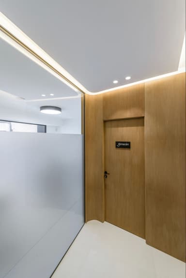  Reforma de Puerta de un almacén en una clínica dental de Madrid con diseño minimalista, acabados en madera y detalles de iluminación moderna.