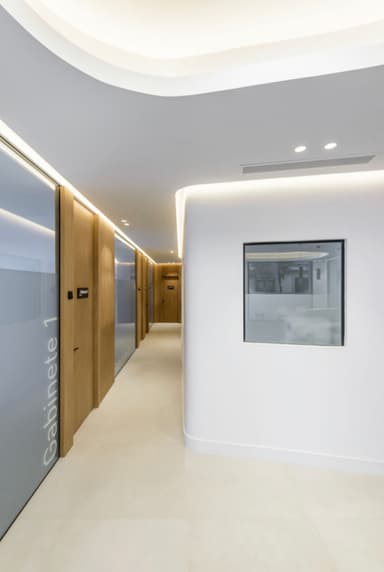 Reforma de Pasillo de una clínica dental en Madrid con diseño moderno, puertas de madera y detalles minimalistas en iluminación.